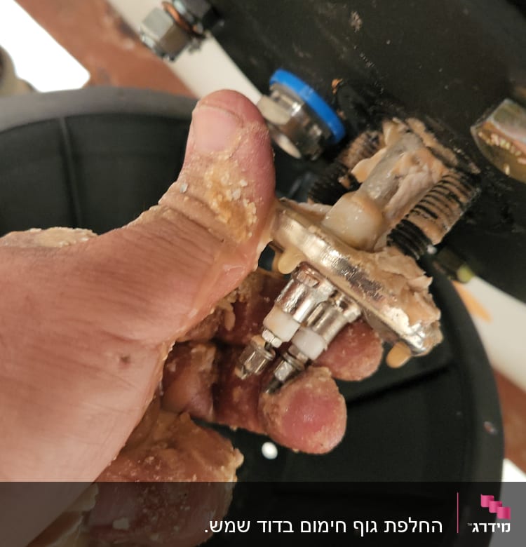 יד מחזיקה חלק מתכת עם ברגים ומחברים